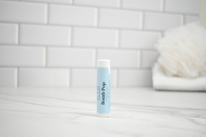 Lip balm tube on a bathroom counter with a tiled wall background