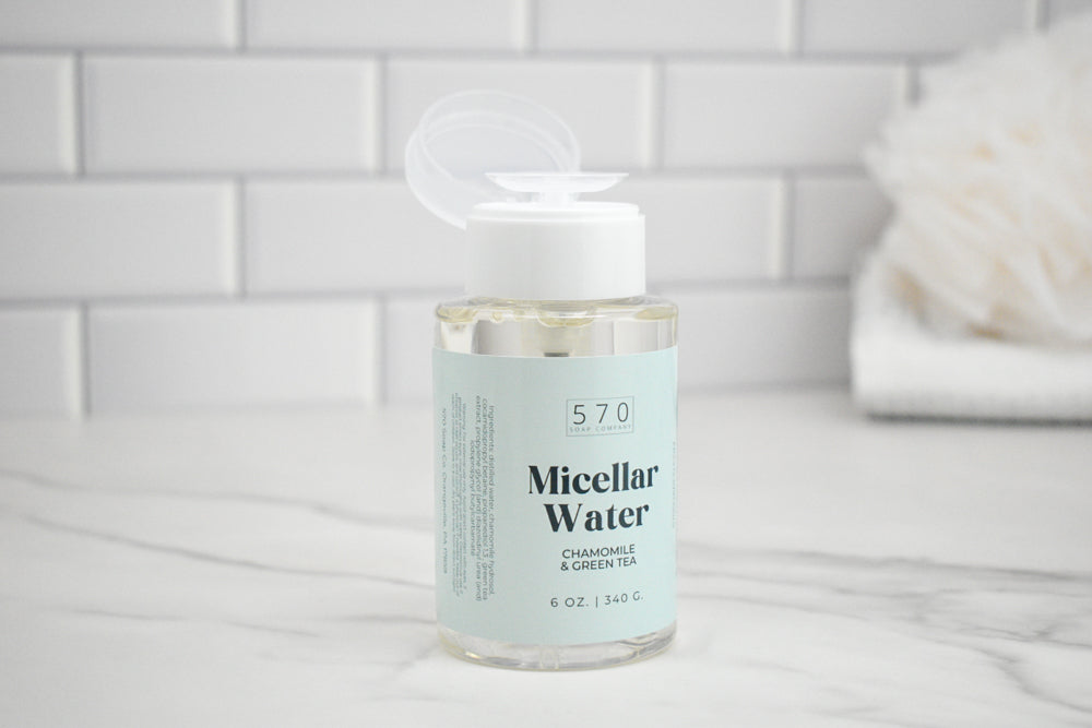Bottle of Micellar Water with a white cap on a marble surface with a tiled wall background