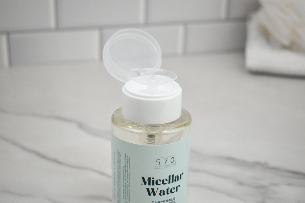 Bottle of micellar water with a white cap on a marble surface.