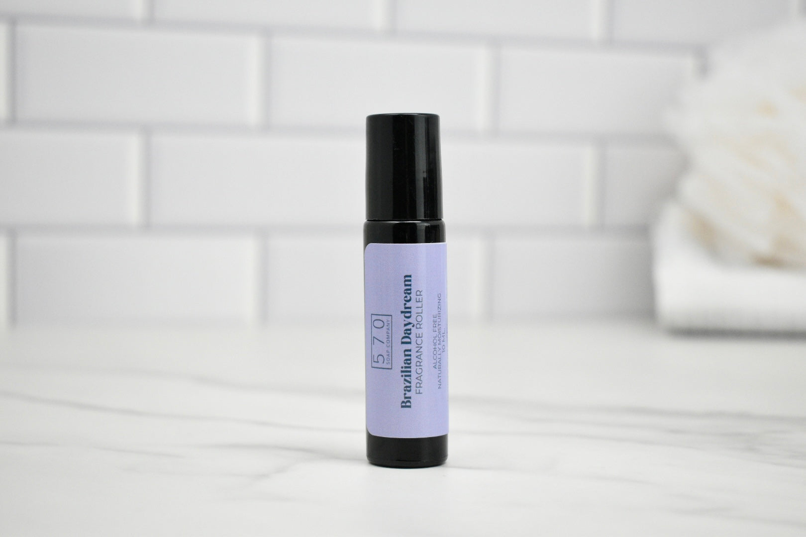 Roll-on bottle with purple label on a white surface with a tiled wall background