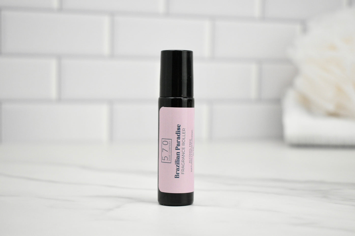 Roll-on bottle with pink label on a white surface with a tiled wall background