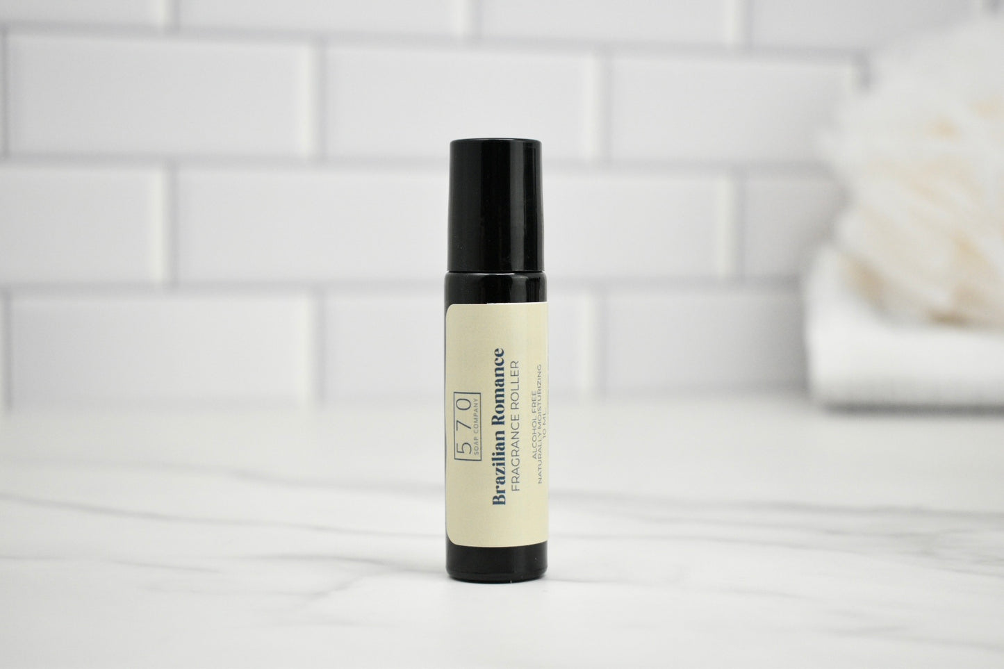 Skincare roller bottle on a white surface with a tiled wall background
