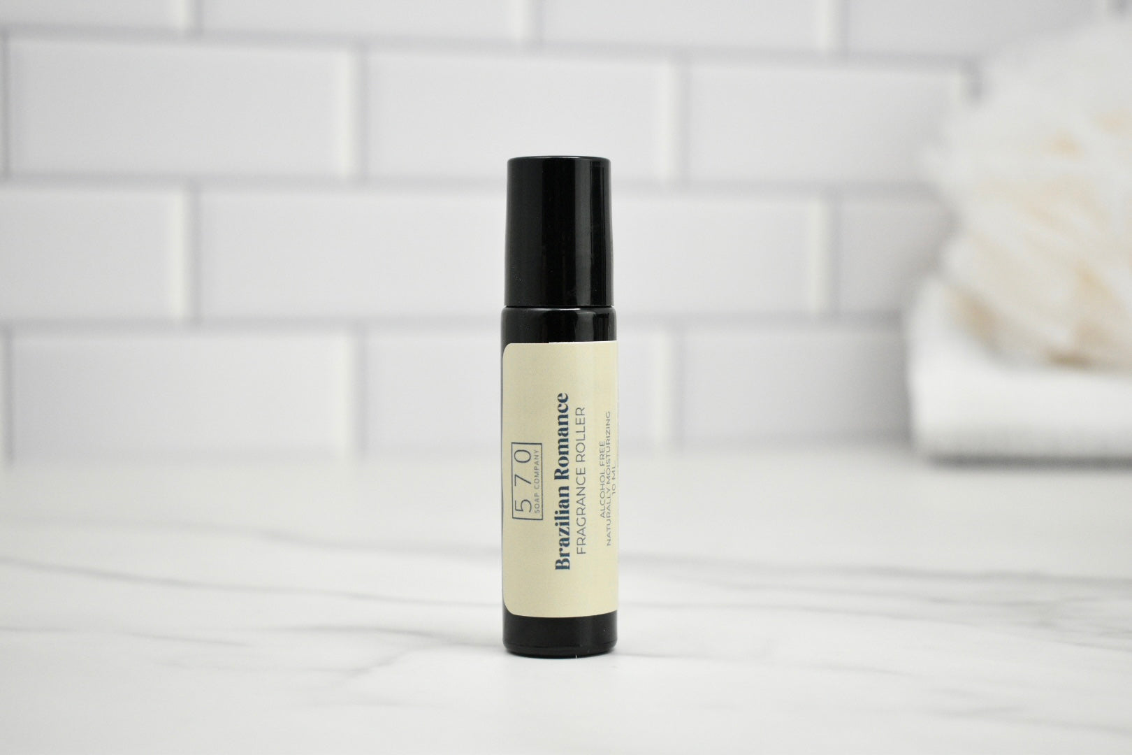 Skincare roller bottle on a white surface with a tiled wall background