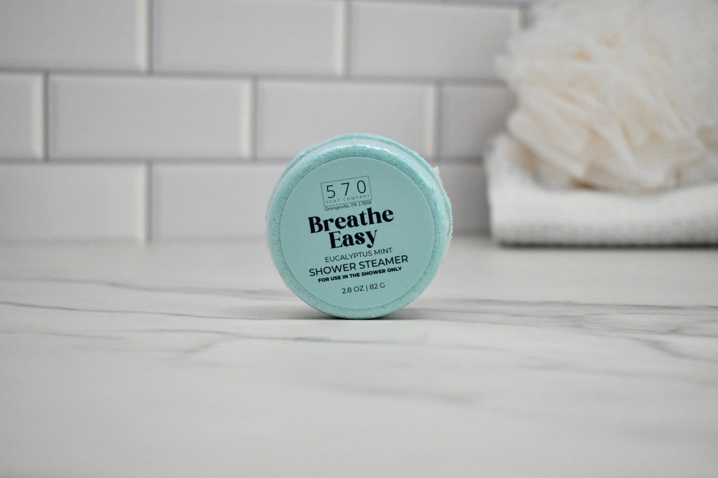 Breathe Easy shower steamer on a bathroom counter with a tiled wall background