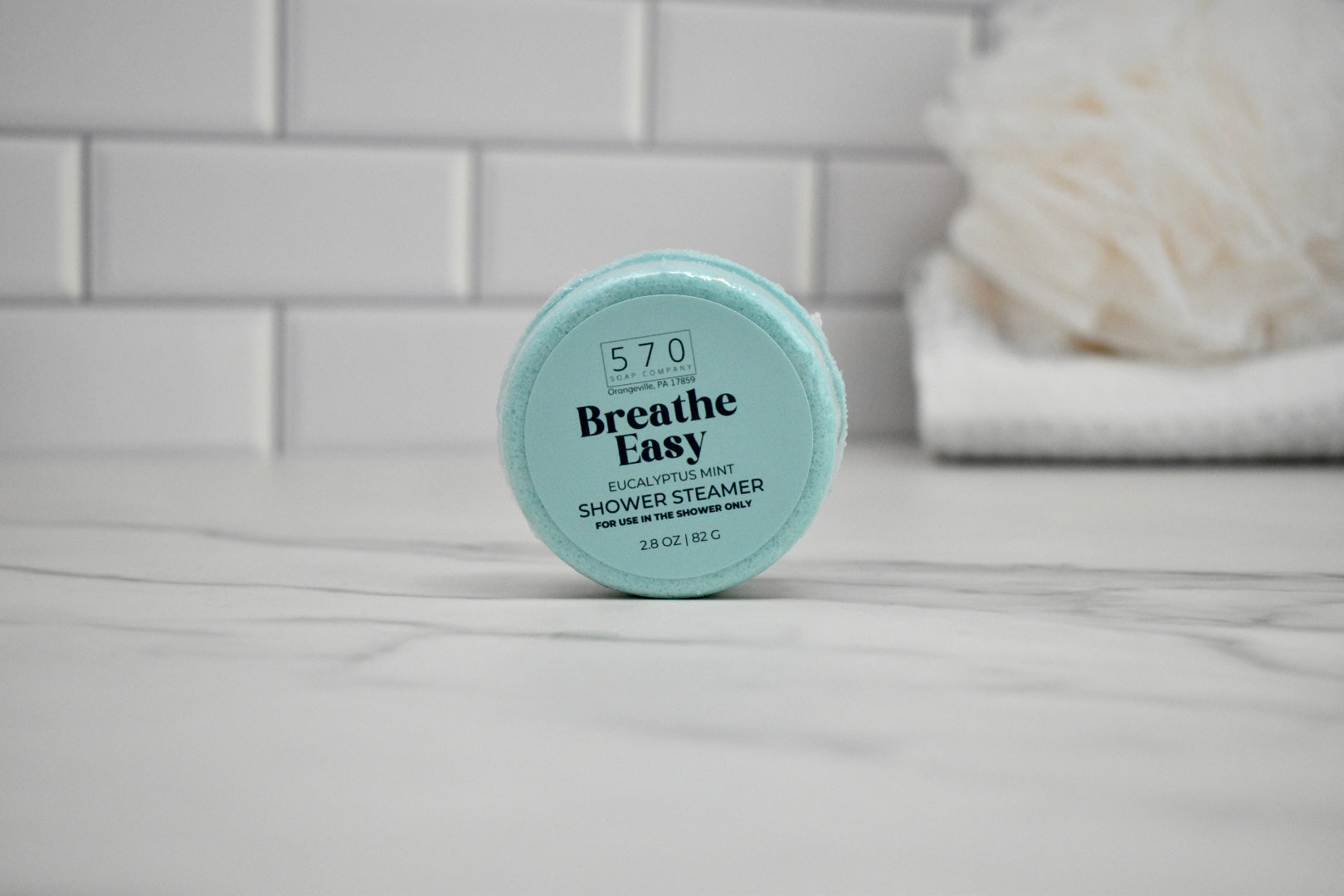 Breathe Easy shower steamer on a bathroom counter with a tiled wall background