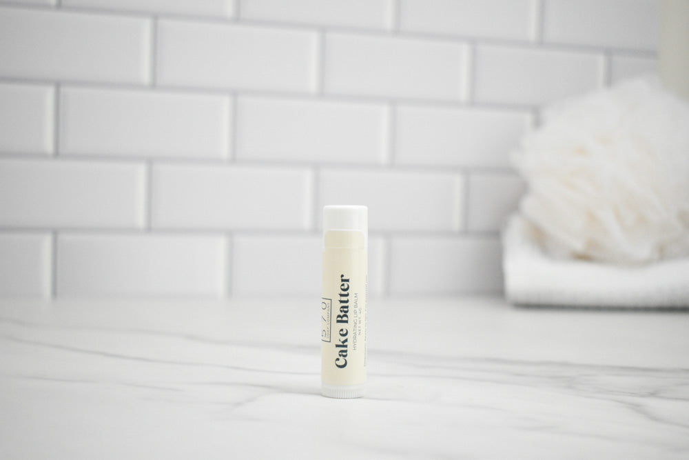 Bottle of cake batter lip balm on a white surface with a tiled wall background