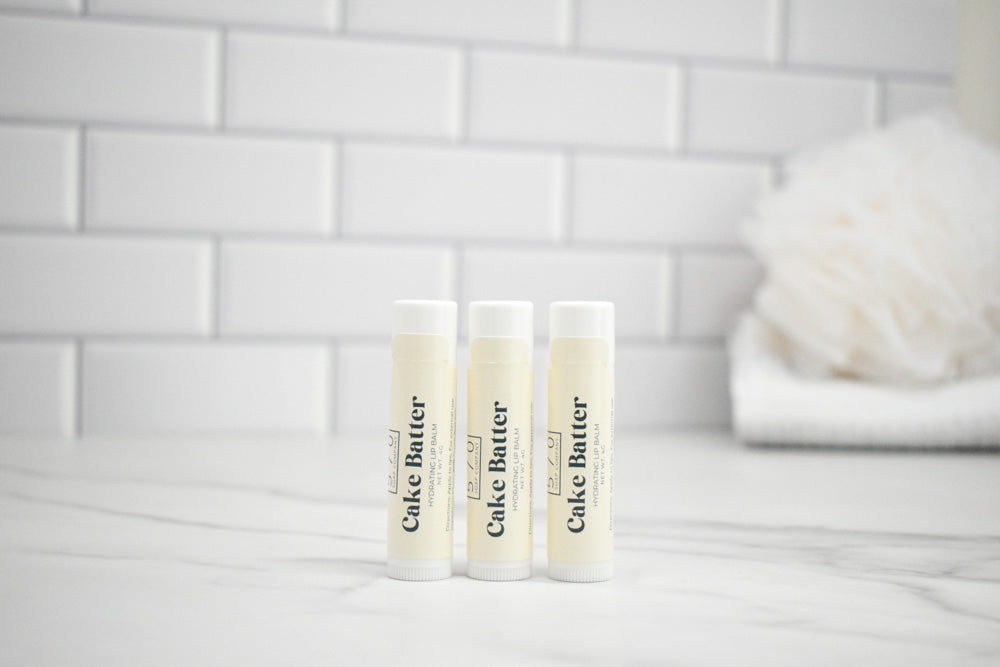 Three tubes of cake butter on a white surface with a tiled wall background