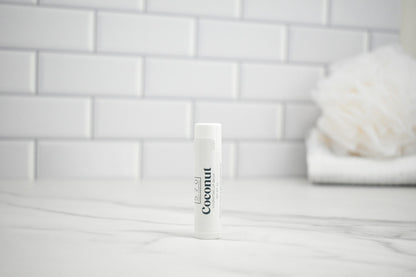 White tube labeled 'Coconut' on a white surface with a tiled wall background