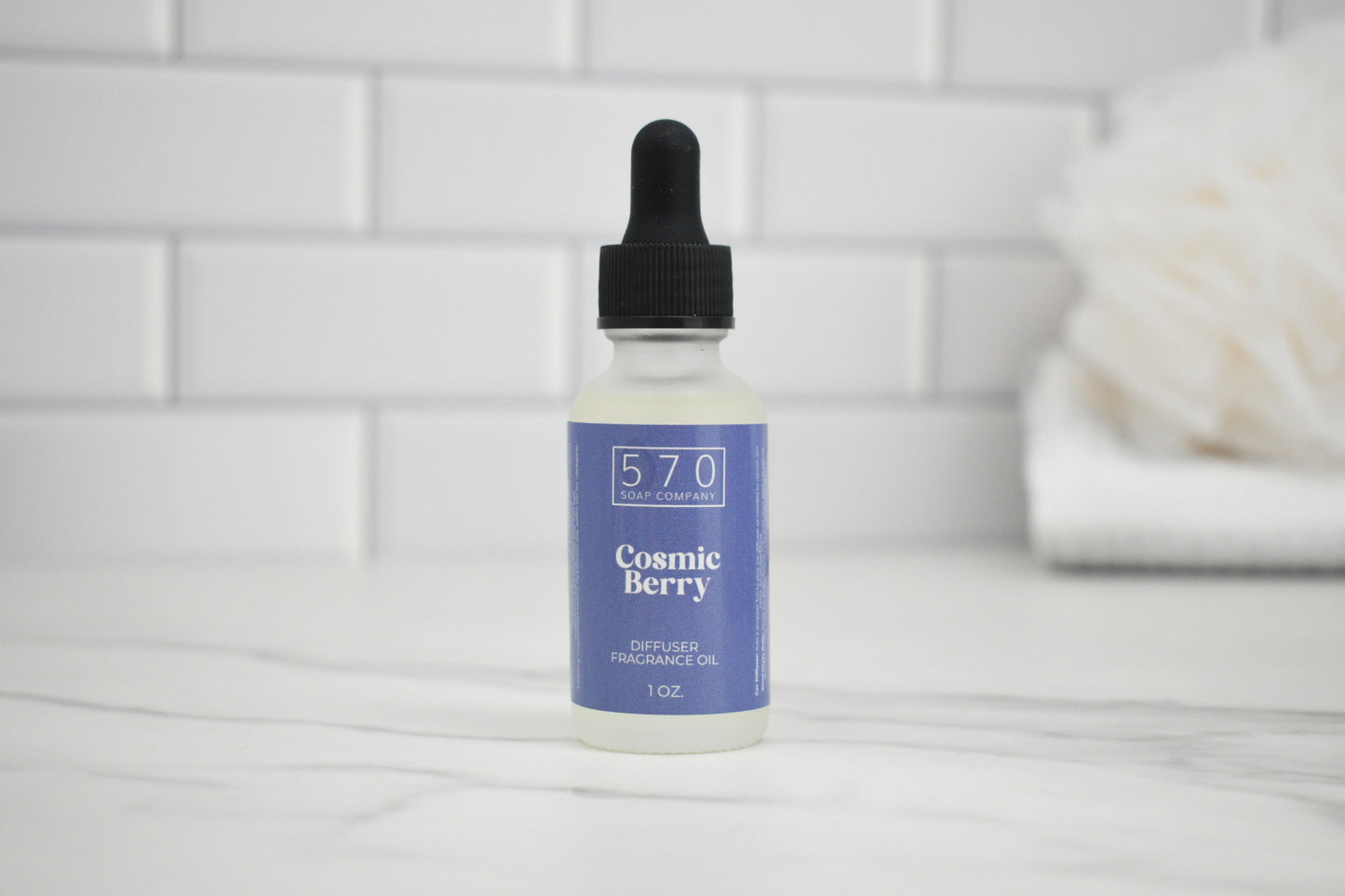 Bottle of Cosmic Berry perfume oil on a white surface with a tiled wall background