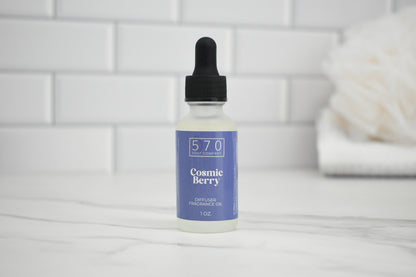 Bottle of Cosmic Berry perfume oil on a white surface with a tiled wall background