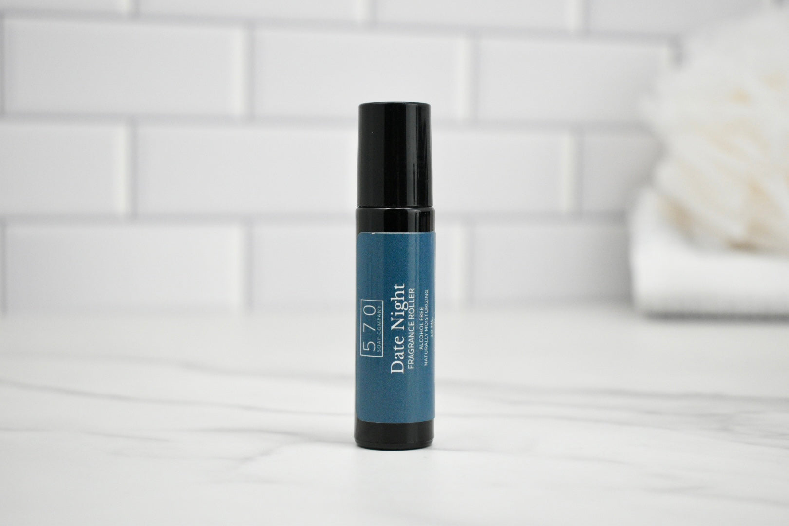Skincare serum bottle labeled 'Date Night' on a white surface with a tiled wall background