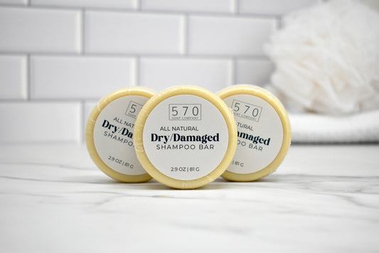 Three all-natural dry damaged shampoo bars on a white tiled surface.