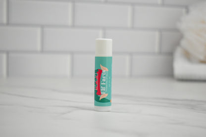 Elf Farts Lip balm stick with a brand logo on a tiled bathroom floor