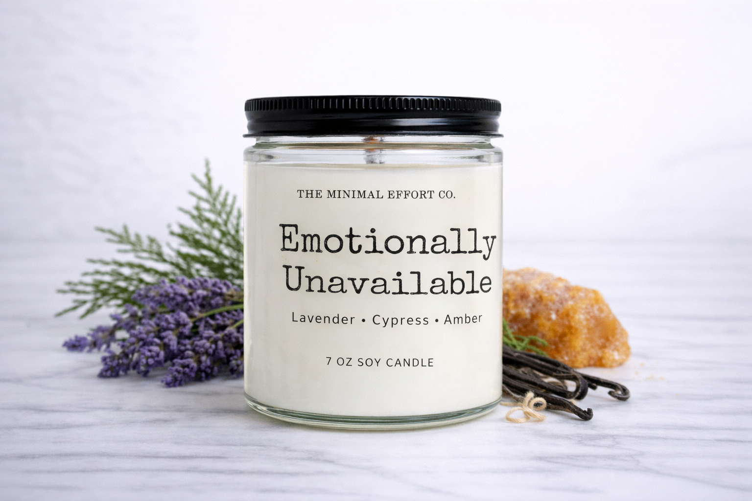 Candle labeled 'Emotionally Unavailable' from The Minimal Effort Co. with lavender and vanilla beans on a white background.