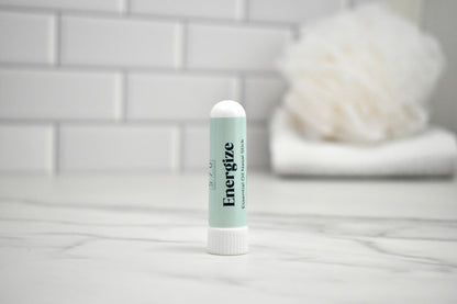 Nasal stick labeled 'Energize' on a bathroom counter with a tiled wall background.