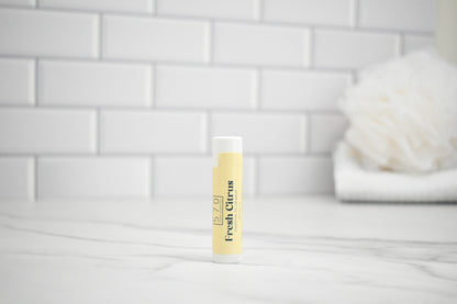 Tube of 'Fresh Citrus' lip balm on a white tiled bathroom counter