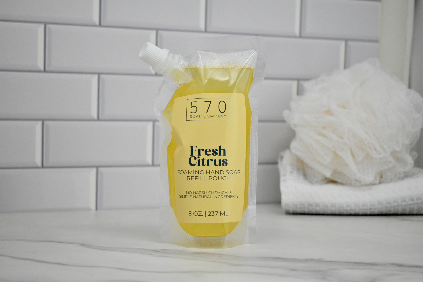 Yellow refill pouch labeled '570' with 'Fresh Citrus' soap on a bathroom counter.
