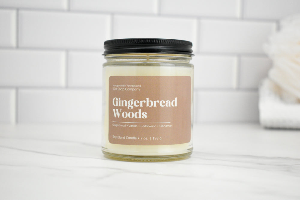 Candle jar labeled 'Gingerbread Woods' on a white surface with a tiled wall background