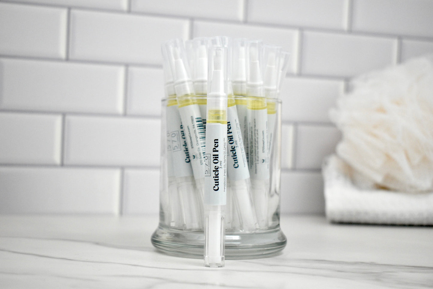 Clear plastic cups with labels on a white surface against a tiled wall background