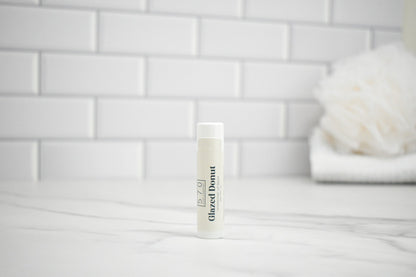 Bottle of Glazed Donut body wash on a bathroom counter with a tiled wall background