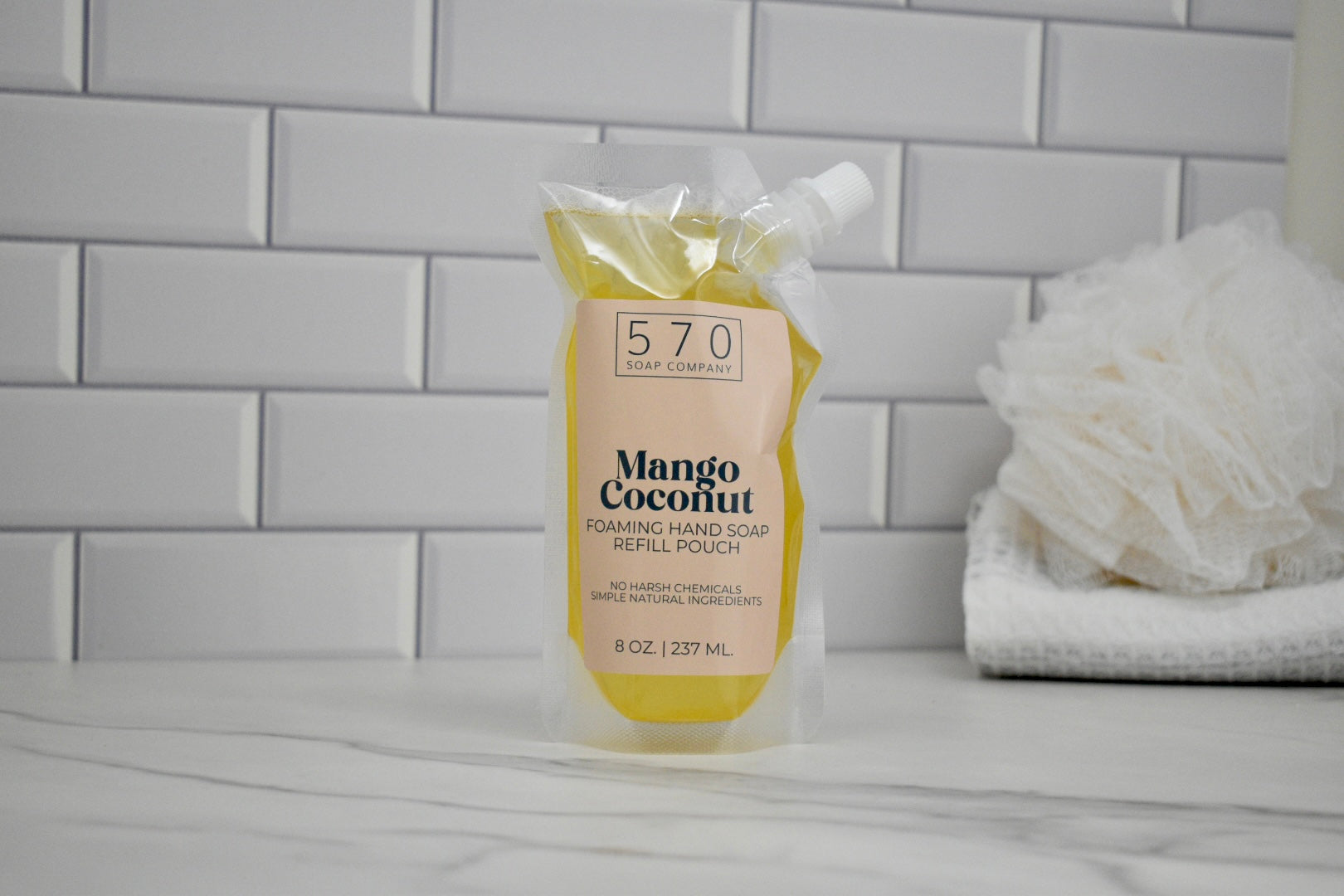 Hand soap bottle labeled '570' with 'Mango Coconut' scent on a bathroom counter.