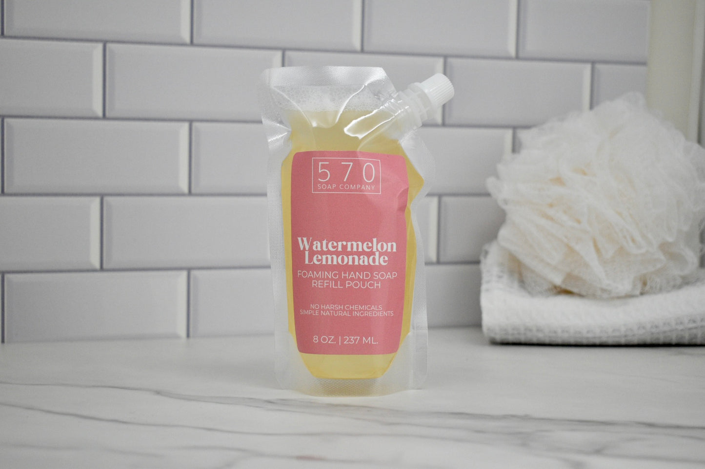 Hand soap bottle labeled '570' with 'Watermelon Lemonade' flavor on a bathroom counter.