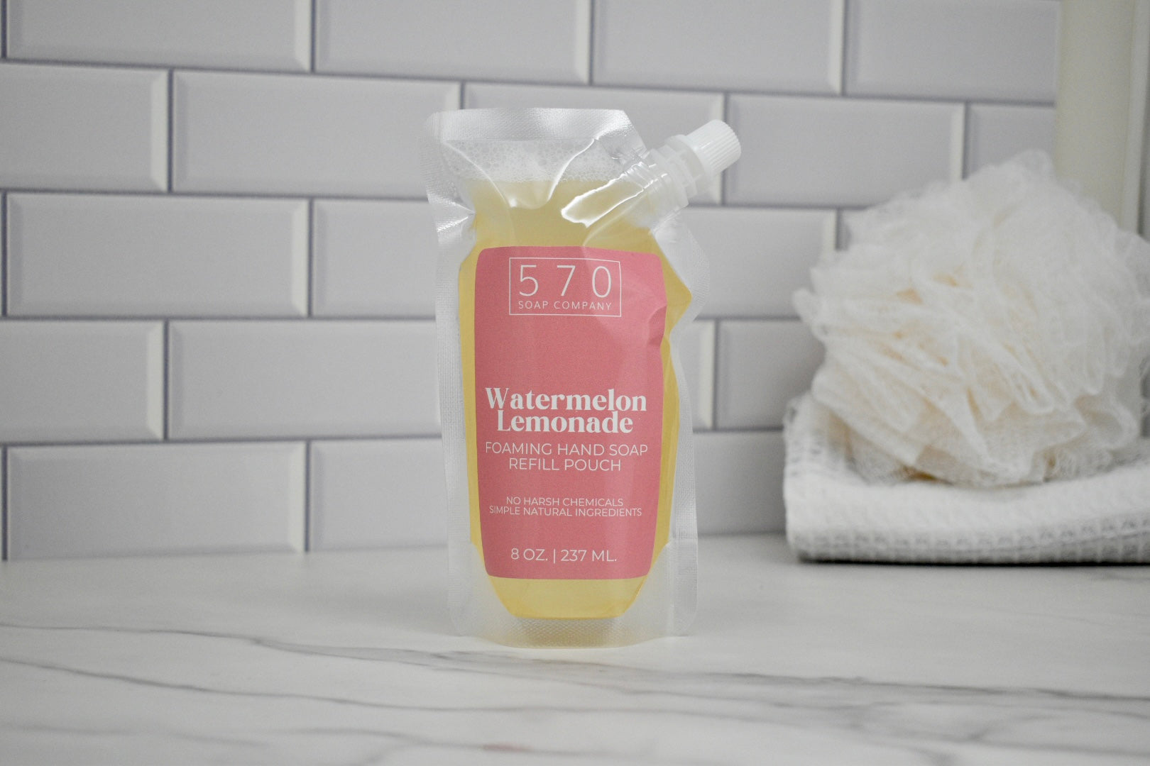 Hand soap bottle labeled '570' with 'Watermelon Lemonade' flavor on a bathroom counter.