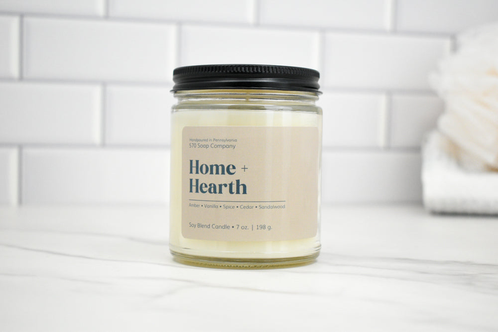 Candle jar labeled 'Home + Hearth' on a white surface with a tiled wall background