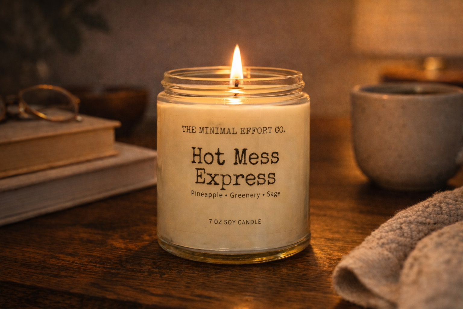 Candle labeled 'Hot Mess Express' from The Minimal Effort Co. on a wooden surface.