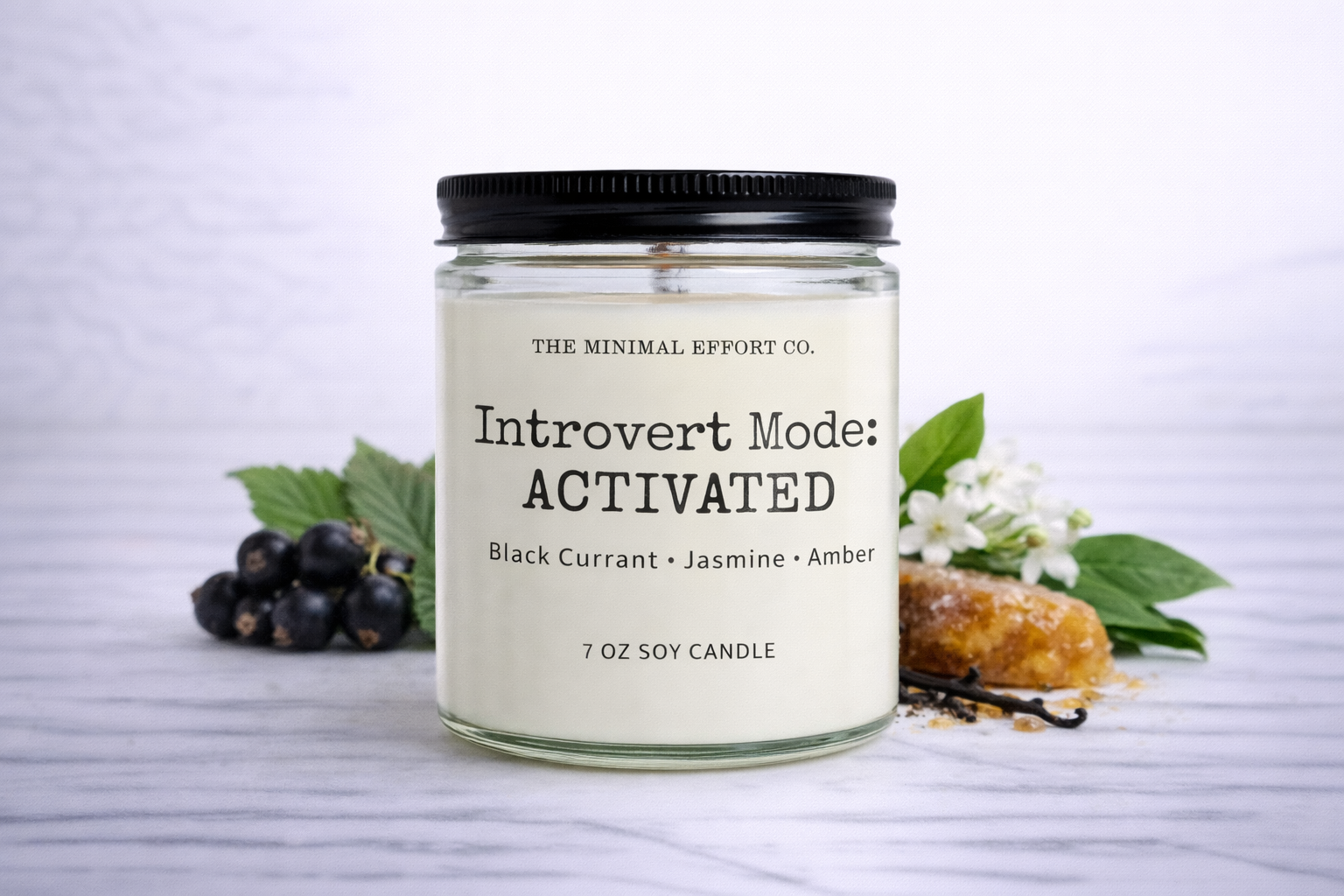 Candle labeled 'Introvert Mode: Activated' with black currants, jasmine, and amber on a white background