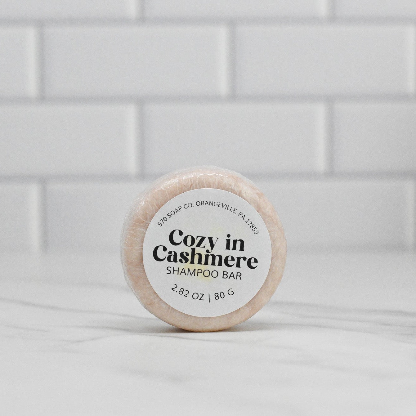 This circular item labeled as the Cozy in Cashmere Shampoo Bar by 570 Soap Co. features nourishing ingredients, making it ideal for eco-conscious hair care.