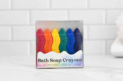 A clear package showcasing six vibrant Unleash Creativity Soap Crayons by 570 Soap Co. is set against a white tile background, featuring kid-friendly crayons in red, orange, yellow, green, blue, and purple for colorful bath time excitement.