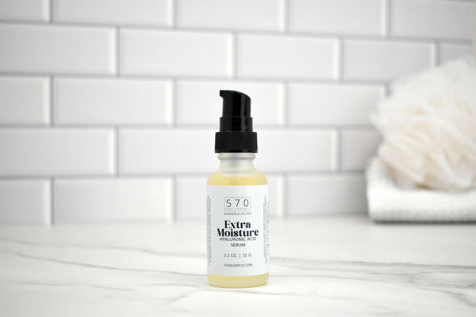 Bottle of 57.0 Extra Moisture Serum on a white tiled bathroom counter