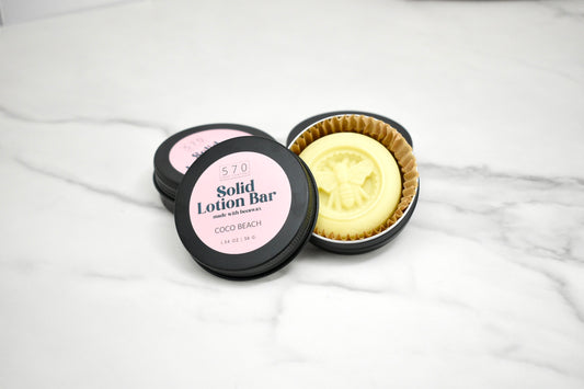 Solid lotion bar in a container on a marble surface