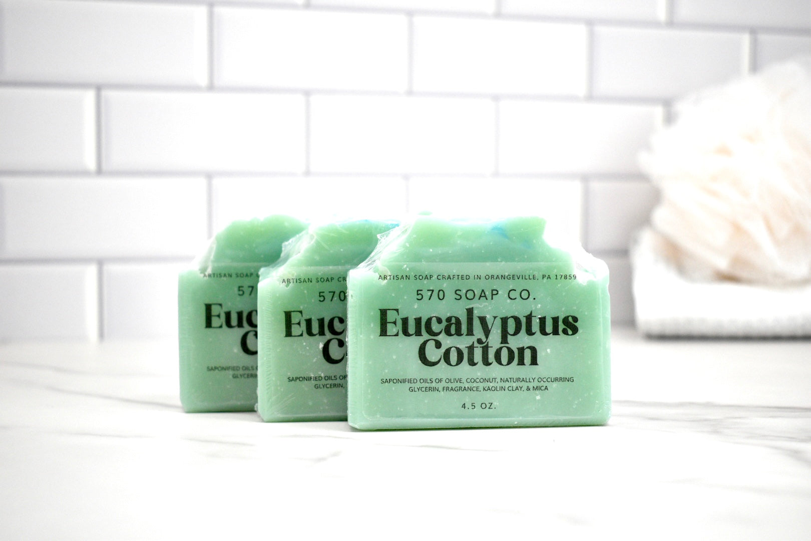 Three bars of Eucalyptus Cotton soap from 570 Soap Co on a white tiled background