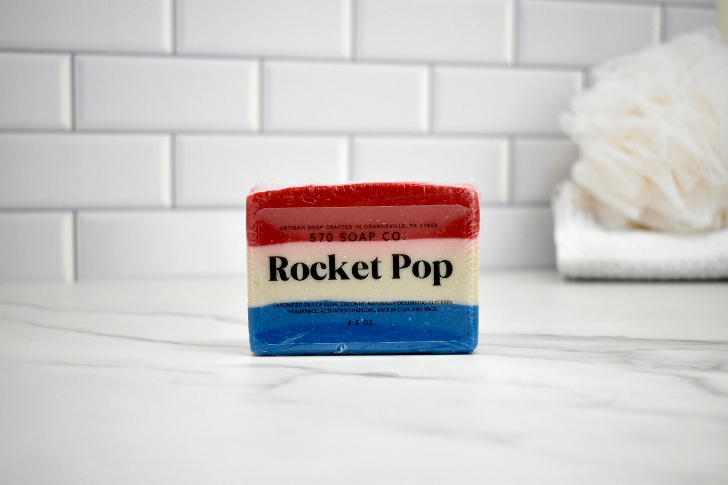 Bar of soap with 'Rocket Pop' branding on a white surface with a tiled wall background