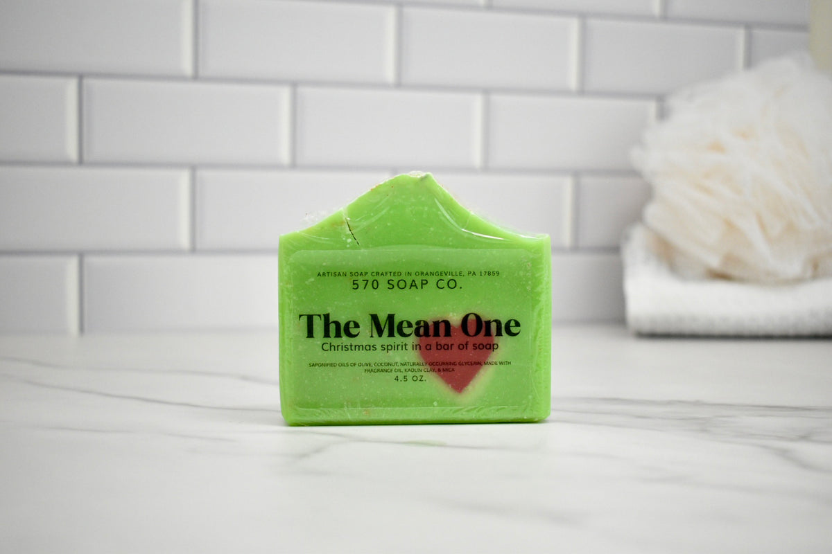 Green soap bar with 'The Mean One' branding on a white surface.