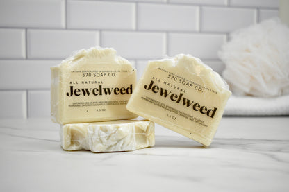 Three bars of Jewelweed soap from 570 Soap Co on a white surface with a tiled wall background.