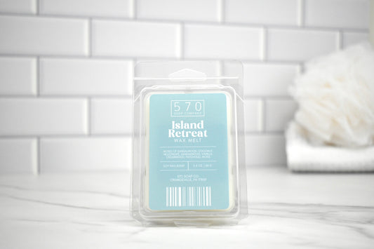 Wax melt packaging labeled 'Island Retreat' on a white surface with a tiled wall background.