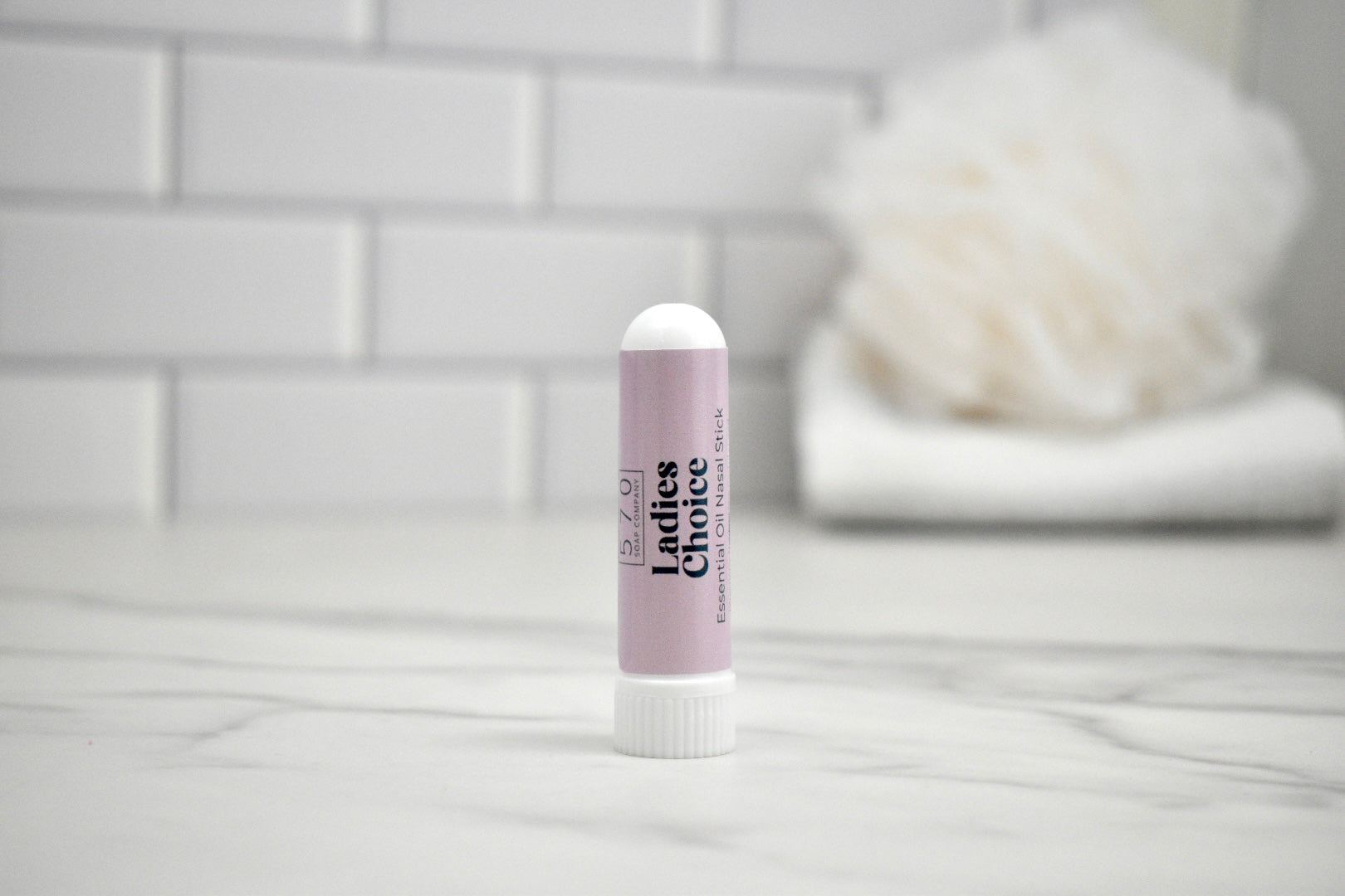 Ladies Choice Nasal Stick on a bathroom counter with a blurred background
