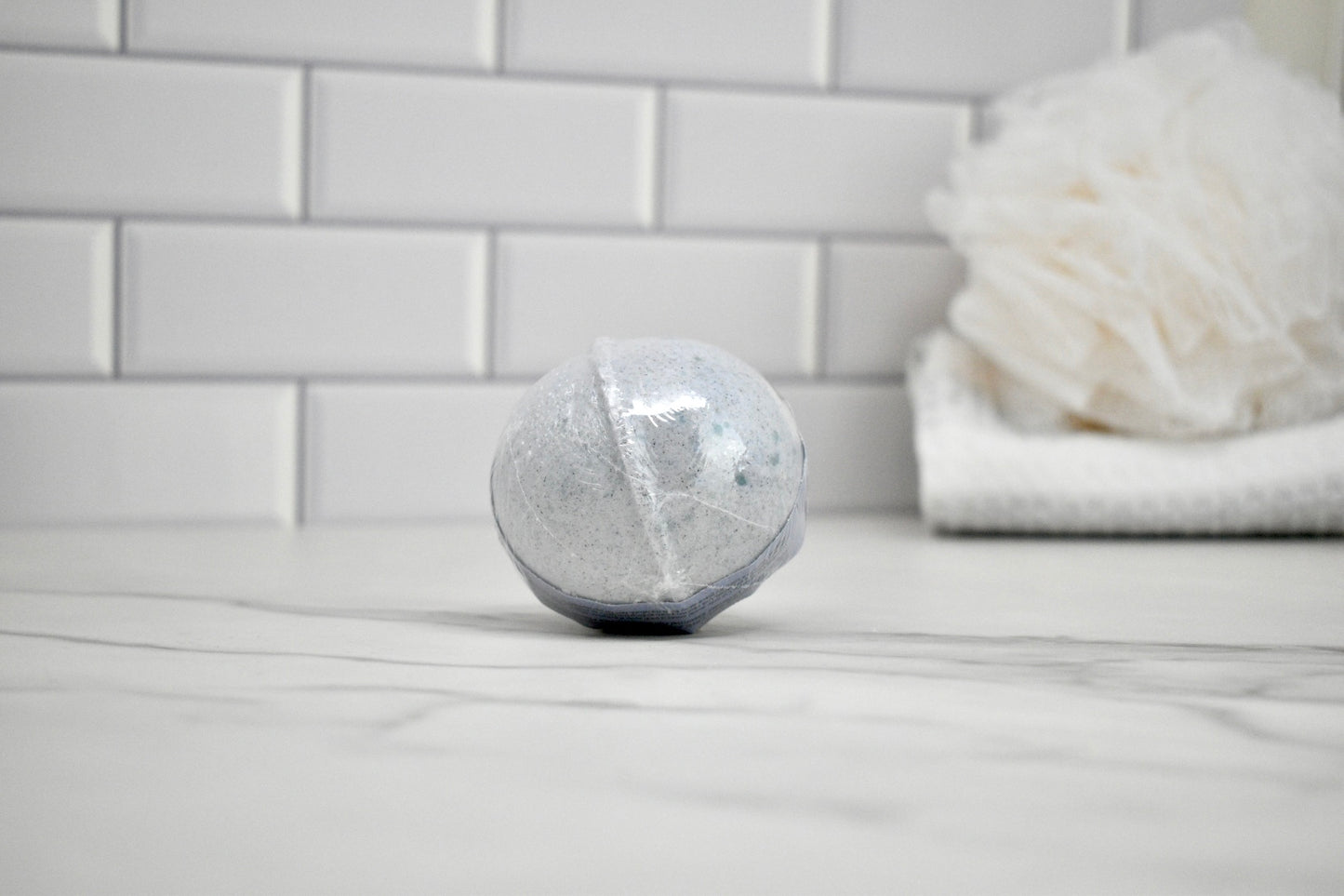Bath bomb on a bathroom counter with a white tiled wall in the background