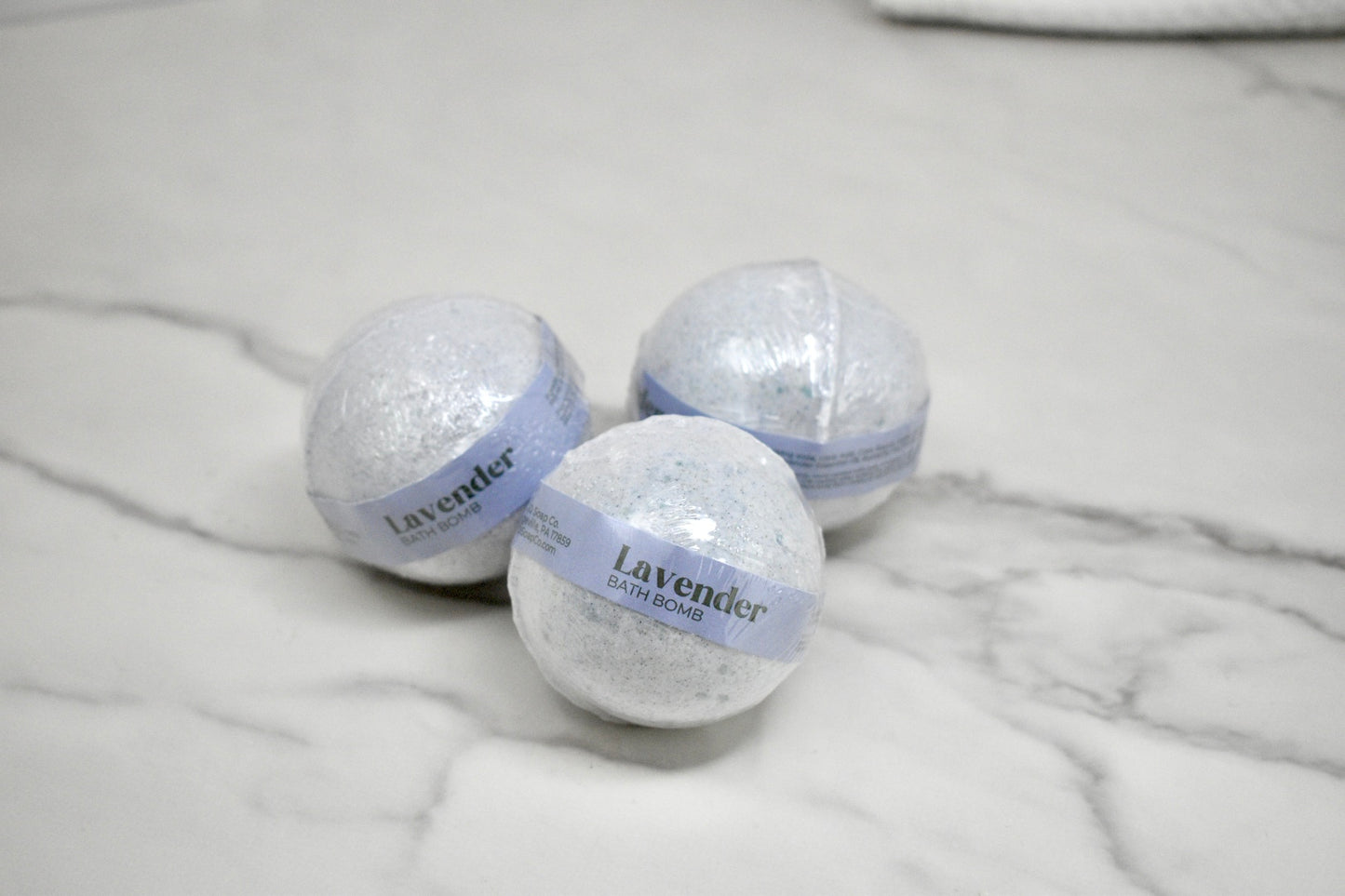 Three lavender bath bombs on a marble surface