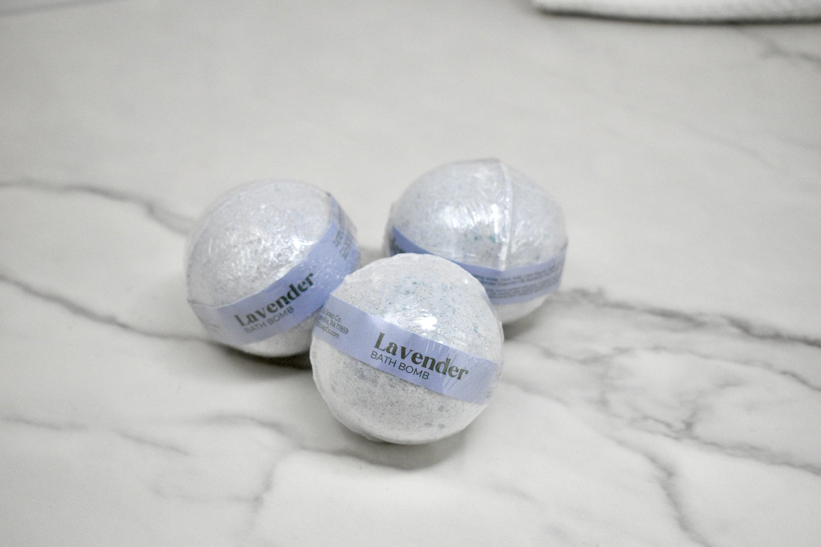 Three lavender bath bombs on a marble surface