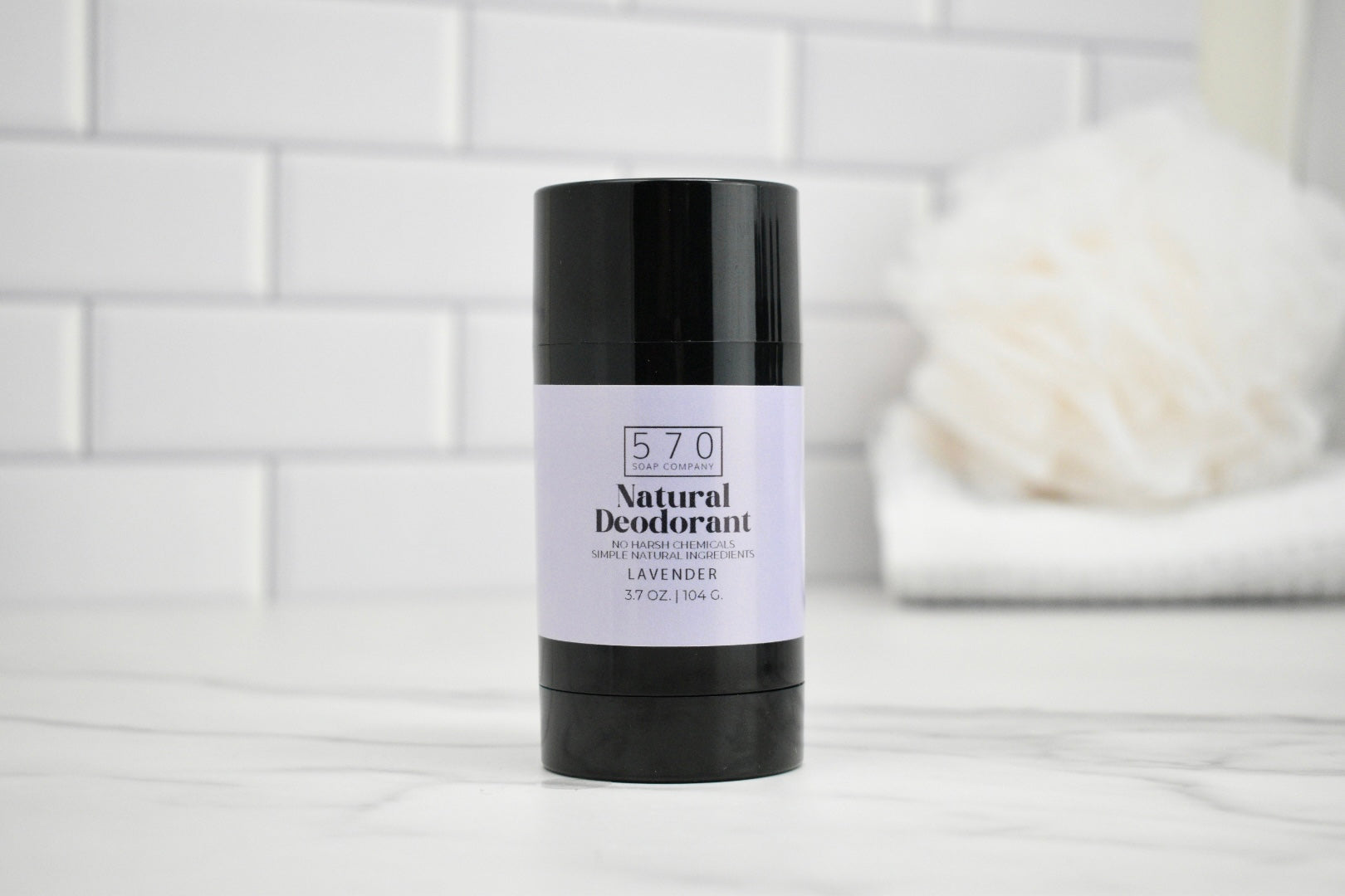 Black deodorant stick with a white label on a light gray surface.