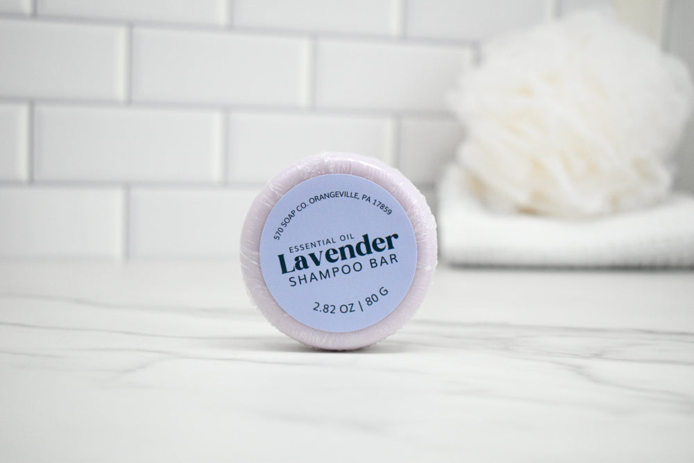 Lavender shampoo bar with a white container on a white surface