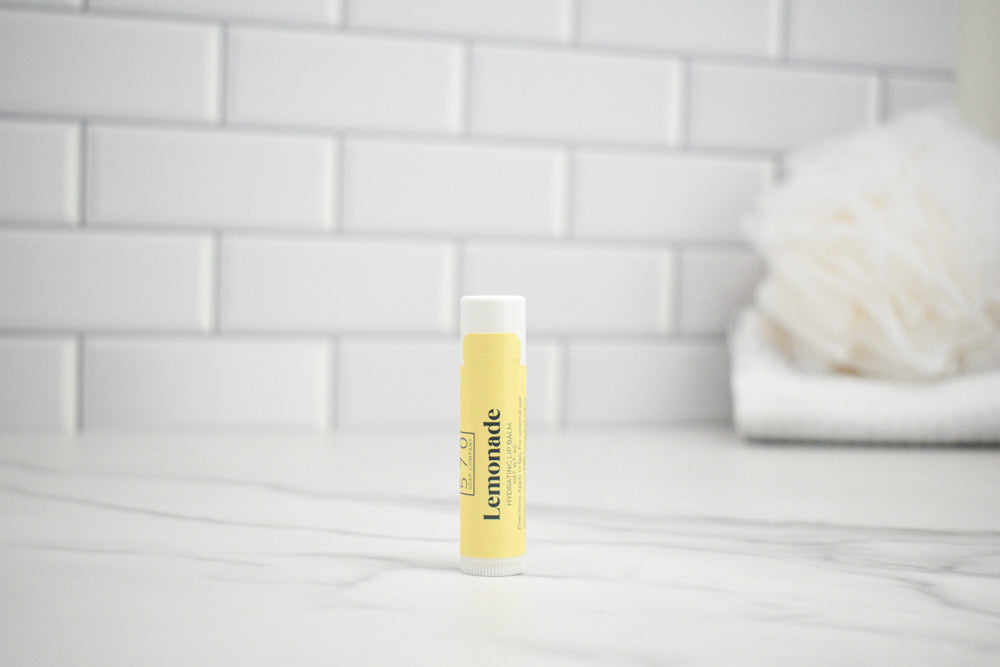 Lip balm with 'Lemonade' branding on a white surface with a tiled wall background