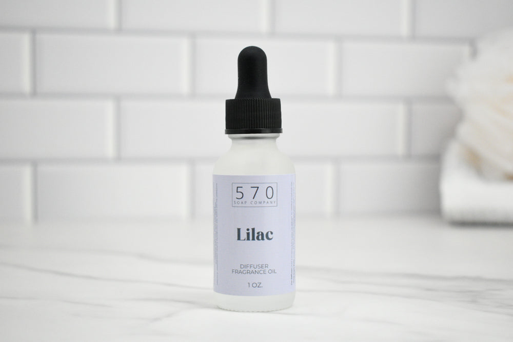 Bottle of 570 Lilac oil with a dropper on a white tiled background