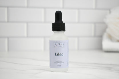 Bottle of 570 Lilac oil with a dropper on a white tiled background