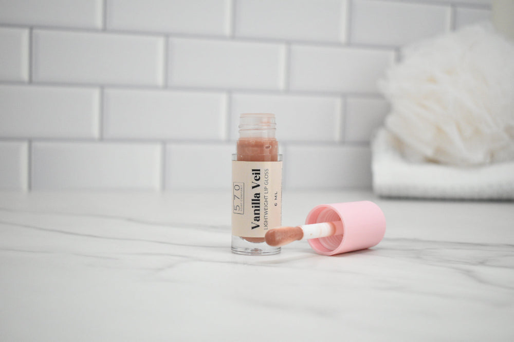 Vanilla Veil lip balm with applicator on a white surface with a tiled wall background