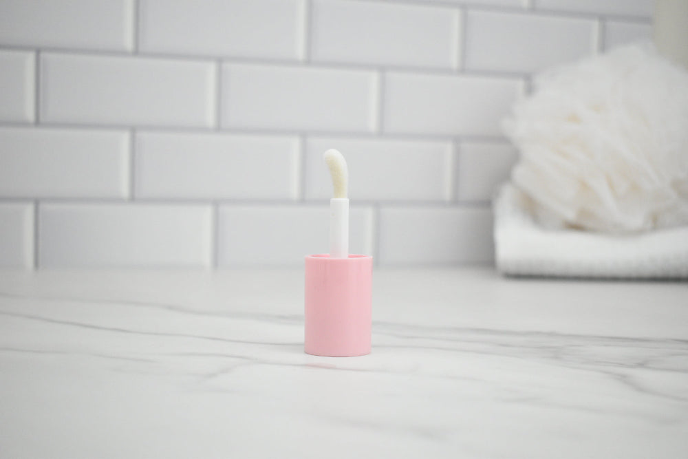 Pink lipgloss lid on a marble counter